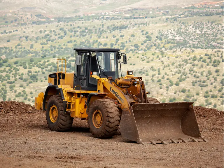 Articulated wheel loader with a full-width bucket standing on a graded earth site
